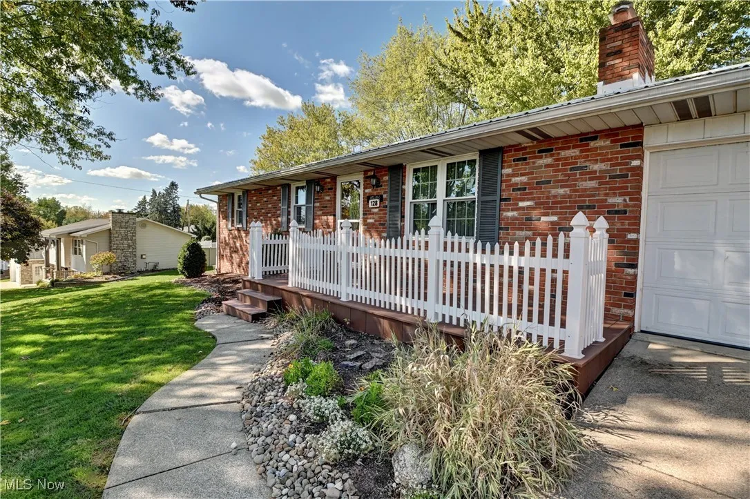 Ranch-style home with brick siding, a deck, a chimney, and a front lawn