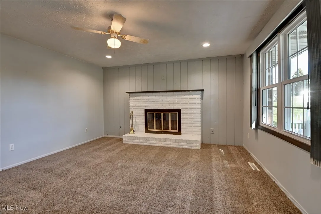 Unfurnished living room with carpet flooring, a fireplace, ceiling fan, recessed lighting, and a textured ceiling