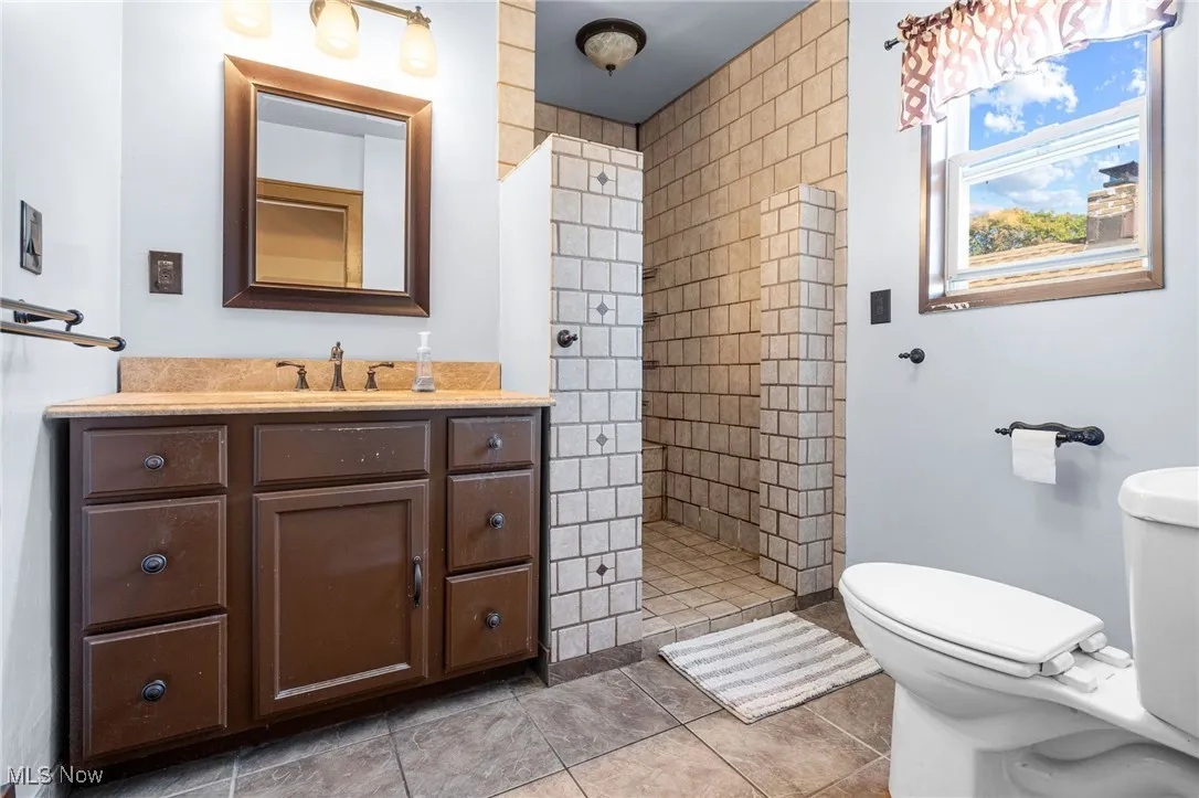 Full bathroom with a walk in shower, vanity, and light tile patterned flooring
