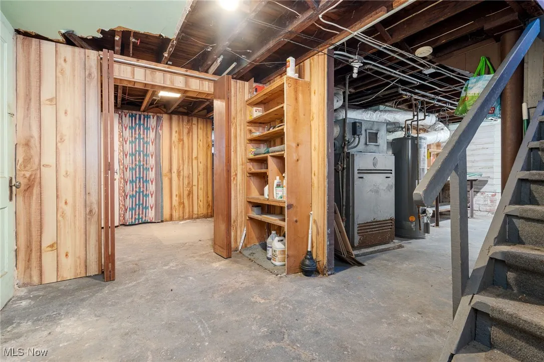 Unfinished below grade area featuring water heater and stairs