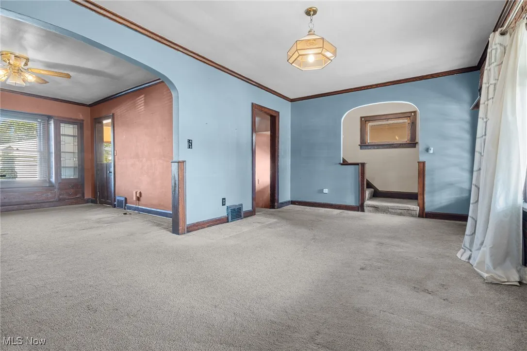 Spare room featuring crown molding, arched walkways, and carpet flooring