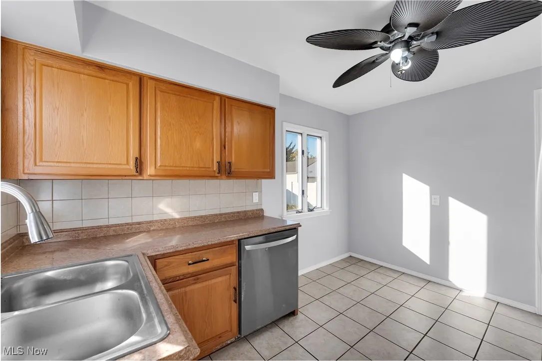 Kitchen featuring backsplash, dishwasher, light tile patterned floors, brown cabinets, and a ceiling fan