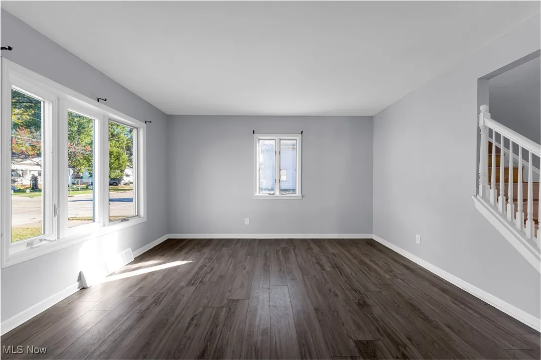 Unfurnished room featuring dark wood finished floors and stairs