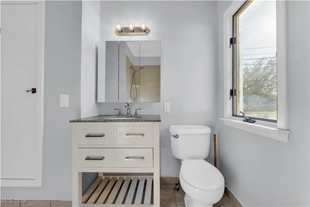 Bathroom with plenty of natural light, vanity, light tile patterned flooring, and a shower