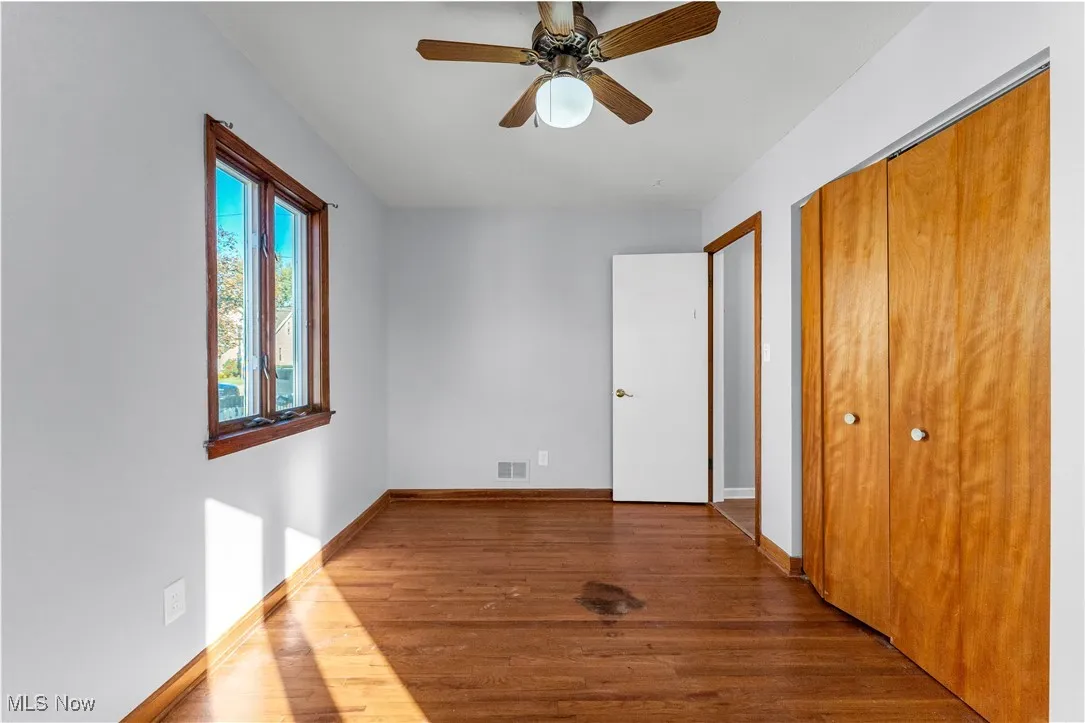 Unfurnished bedroom with dark wood-style floors, a closet, and ceiling fan