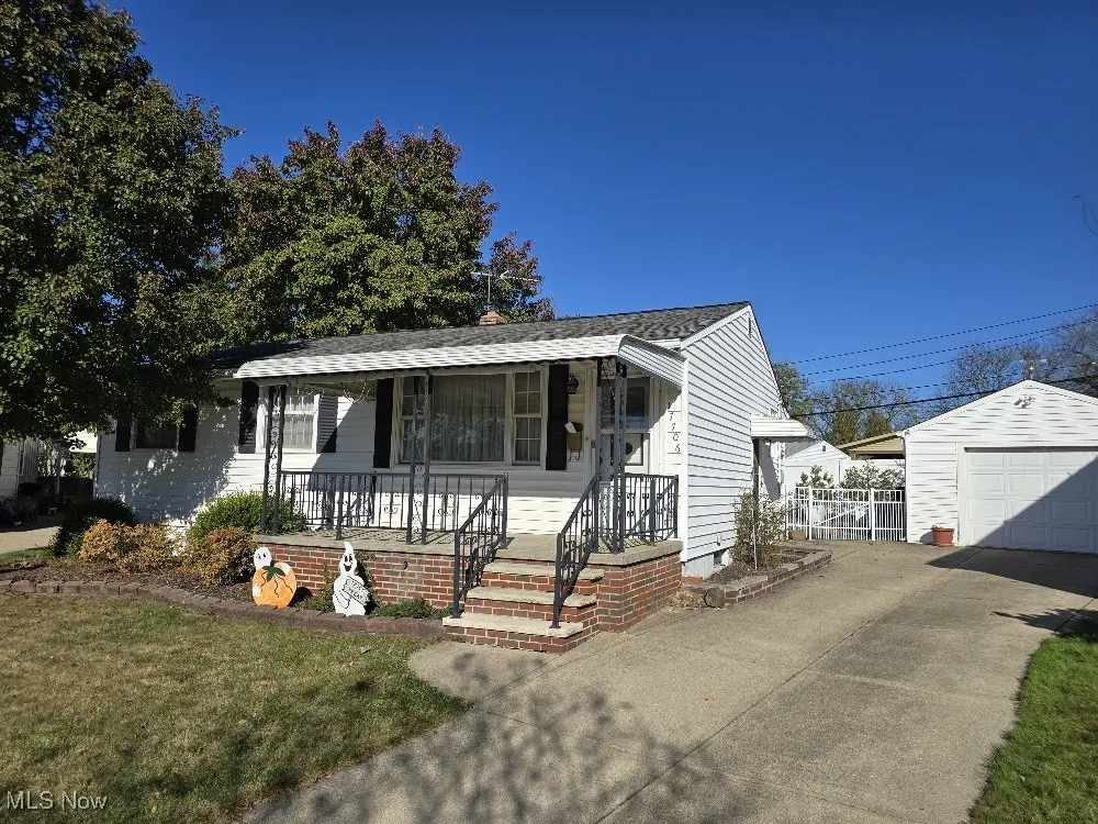 View of front of house featuring a porch, concrete driveway, a front lawn, and a garage.