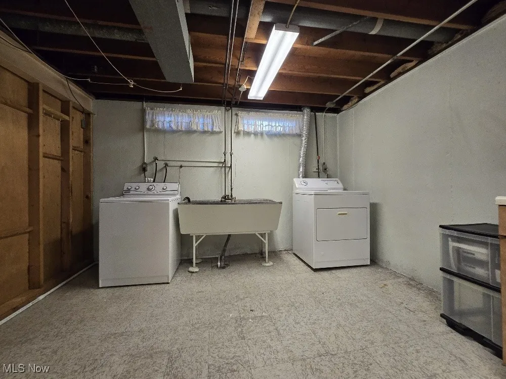 Washroom with light flooring and washer and clothes dryer.