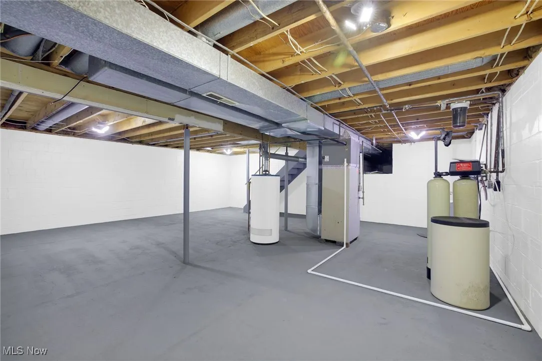 Unfinished below grade area with heating unit, a water softener, and water heater