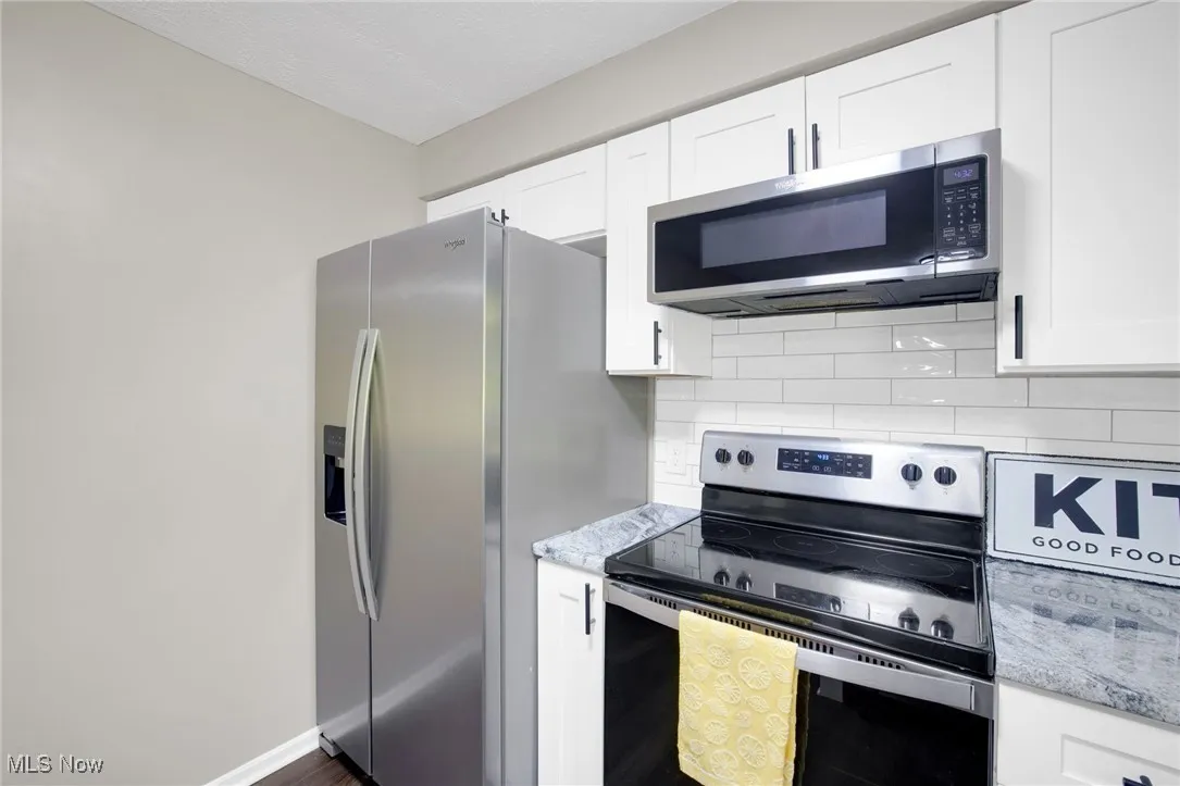 Kitchen featuring appliances with stainless steel finishes, white cabinets, and decorative backsplash