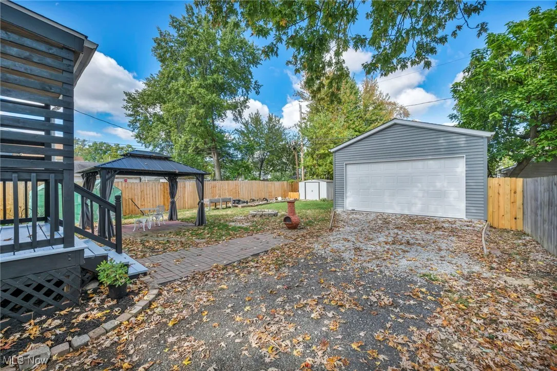 Fenced backyard featuring a gazebo, a detached garage, a storage shed, and a wooden deck