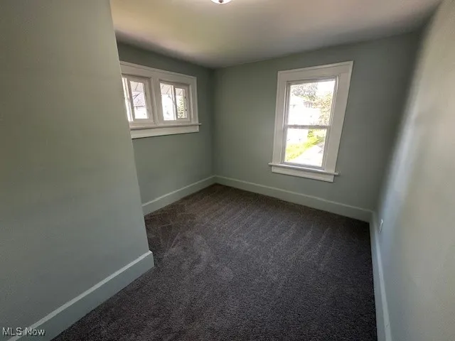 Spare room with dark colored carpet and plenty of natural light
