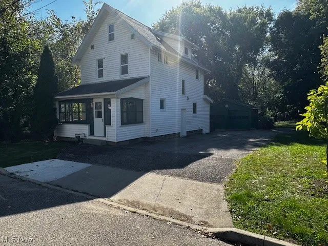 View of front of house with an outbuilding, a garage, and a sunroom