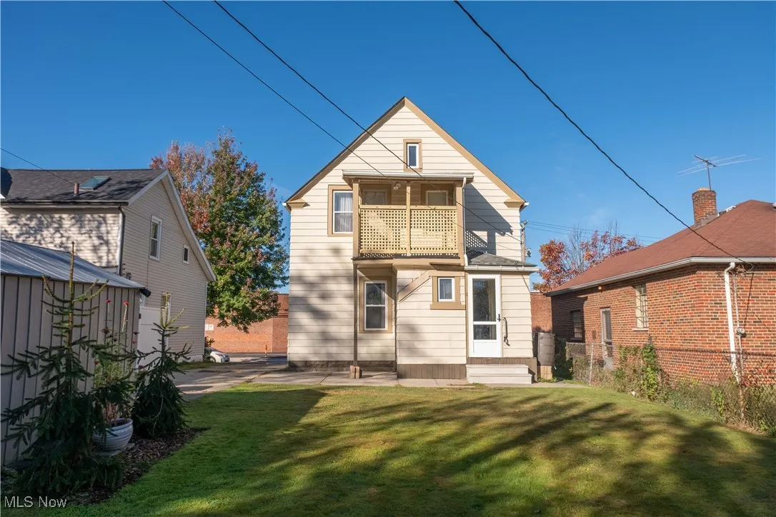 Rear view of house featuring a balcony and a lawn