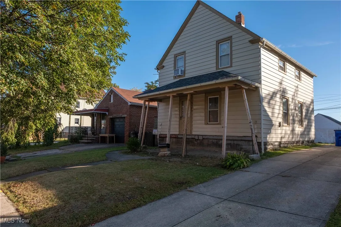 View of front facade with a porch, a front yard, and a chimney