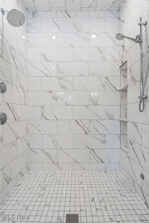 Gorgeous tile owners shower with multiple shower heads along with main rain head  
