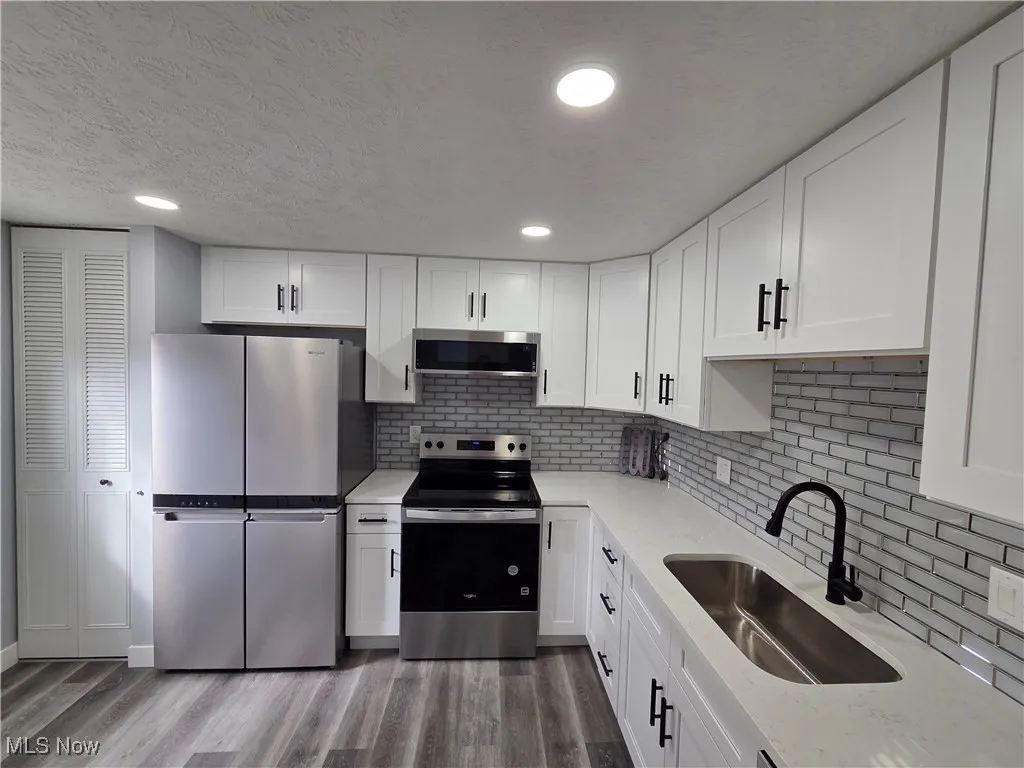 Kitchen featuring stainless steel appliances, white cabinets, quartz countertops, and recessed lighting