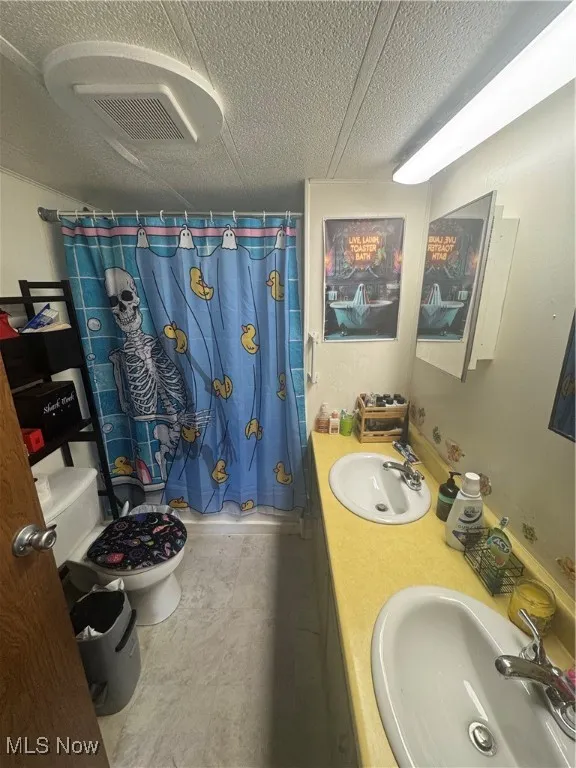 Full bathroom with a stall shower, double vanity, and a textured ceiling