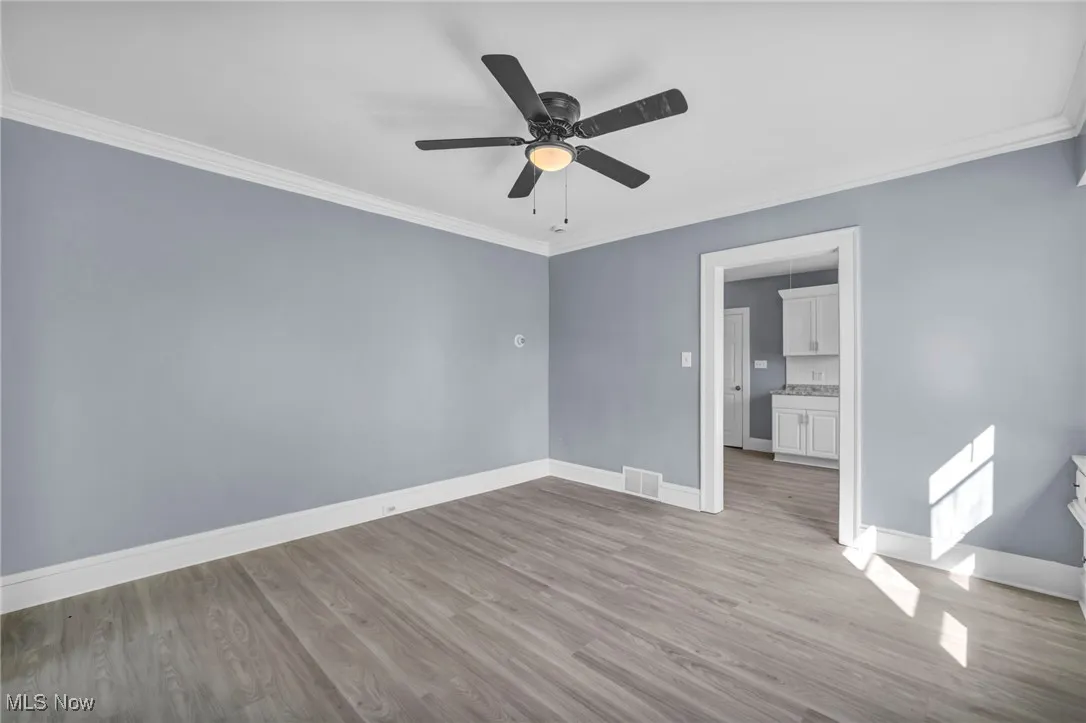 Spare room featuring ornamental molding, light wood finished floors, and ceiling fan