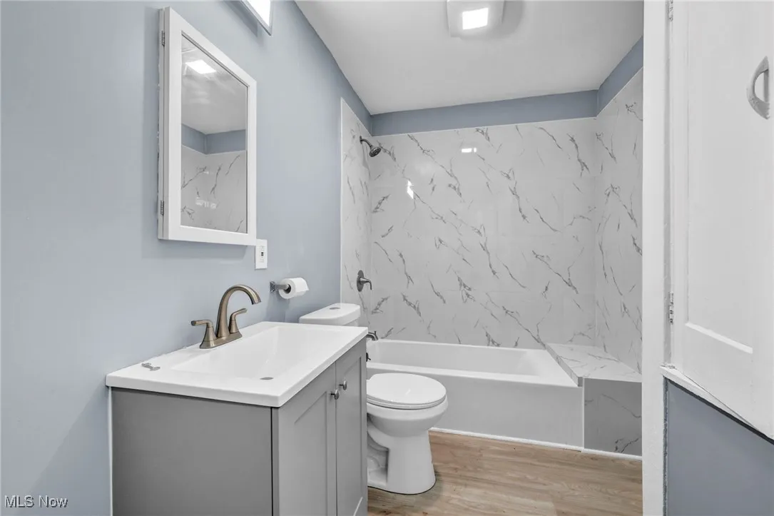 Full bath with vanity, shower / bathtub combination, and light wood-style floors