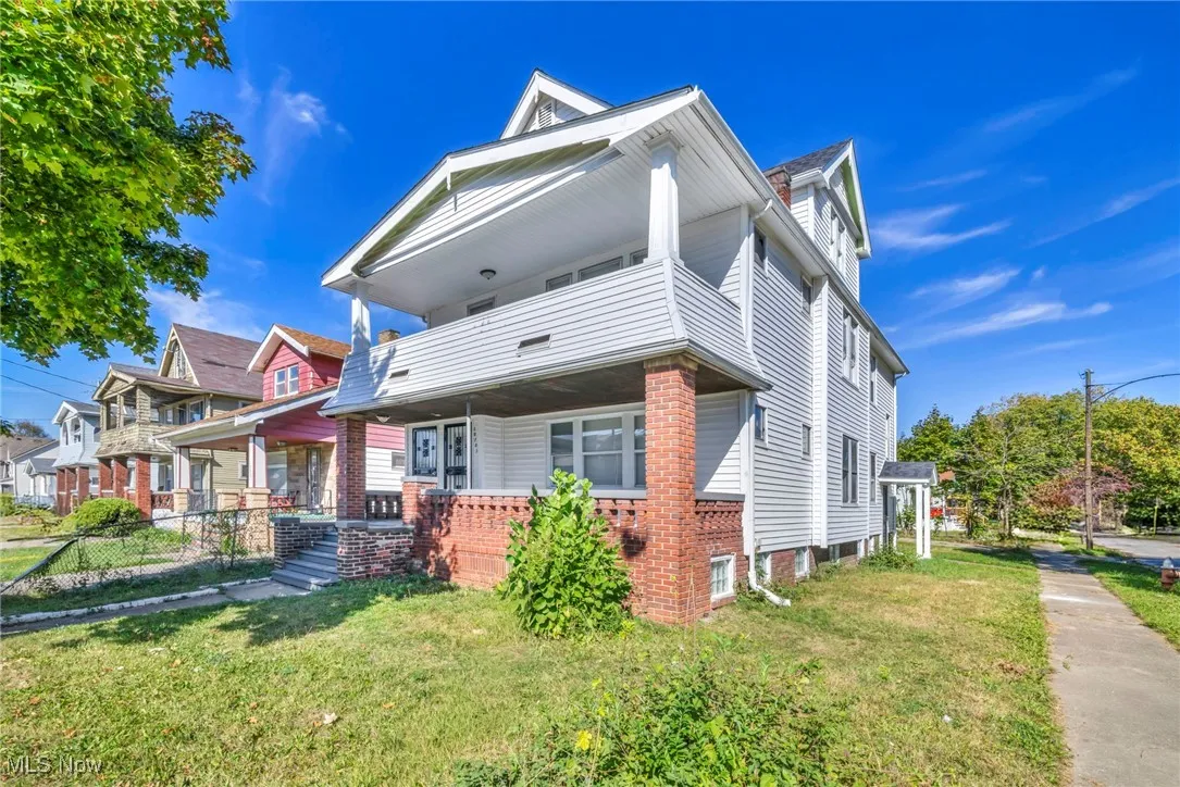 View of front of property featuring covered porch, a front lawn, and a balcony