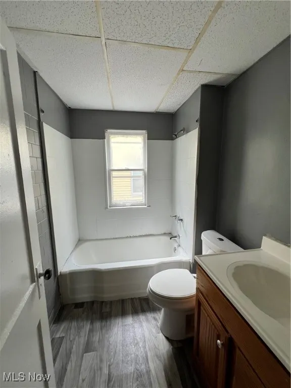Bathroom with bathing tub / shower combination, vanity, dark wood-style flooring, and a drop ceiling
