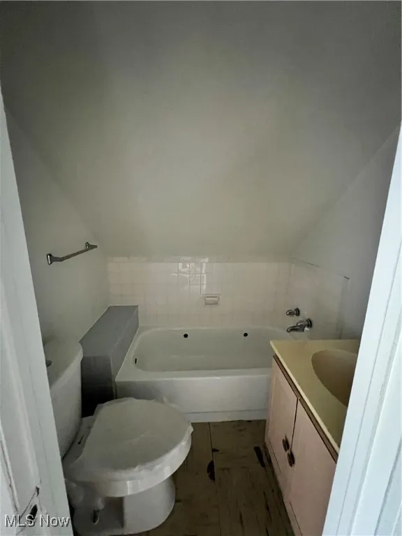 3rd floor loft Full bathroom with vanity, a garden tub, and lofted ceiling