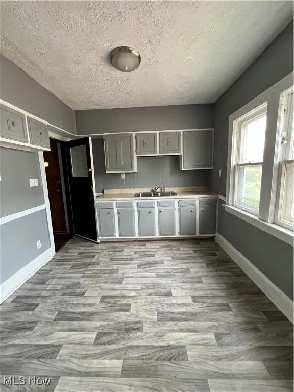 Kitchen featuring gray cabinets, light wood-type flooring, a textured ceiling, and light countertops