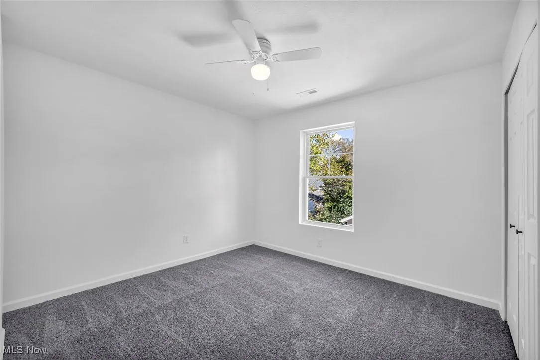 Carpeted empty room featuring baseboards and ceiling fan