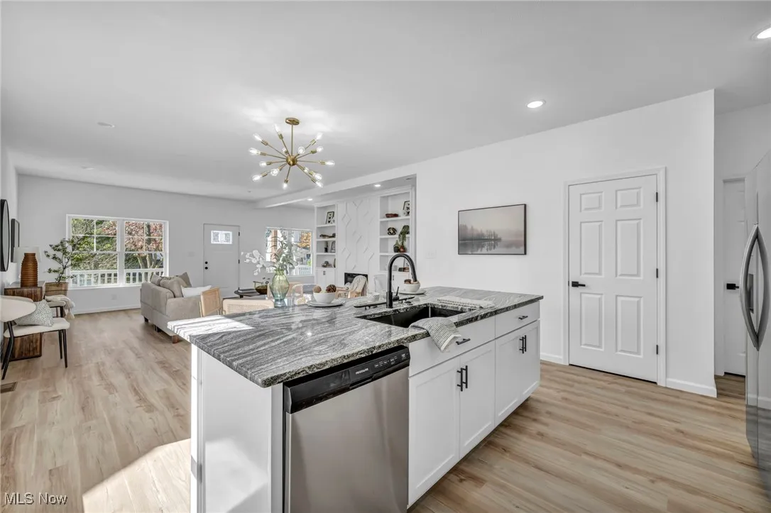 Kitchen featuring white cabinets, dark stone countertops, appliances with stainless steel finishes, light wood-style floors, and a​​‌​​​​‌​​‌‌​‌‌​​​‌‌​‌​‌​‌​​​‌​​ chandelier
