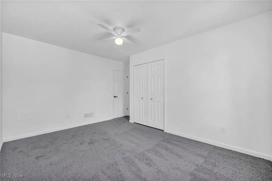 Unfurnished bedroom featuring carpet, ceiling fan, and a closet