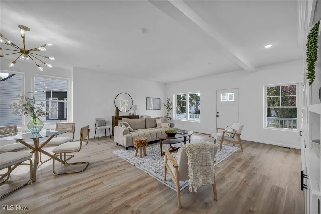 Living room with light wood-style flooring, beamed ceiling, a chandelier, and recessed lighting