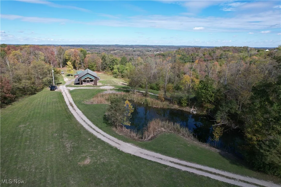 View from above of property with a heavily wooded area and a nearby body of water