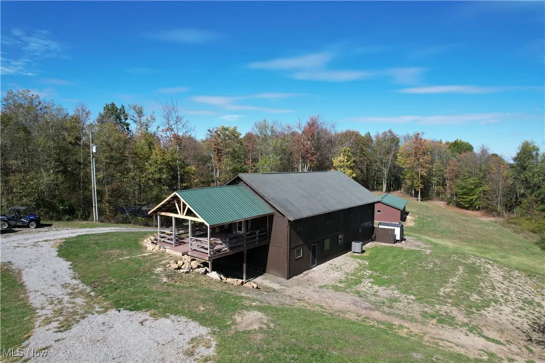View of outbuilding featuring a view of trees and driveway