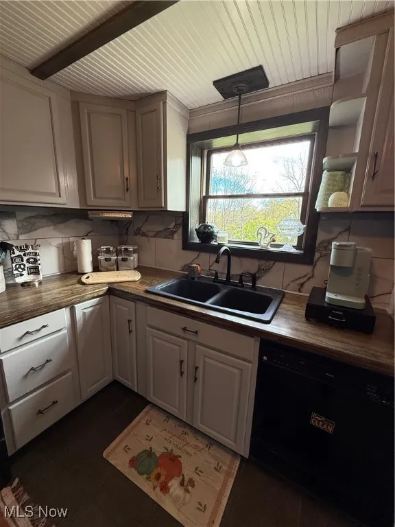 Kitchen with dishwashing machine, backsplash, decorative light fixtures, and dark countertops