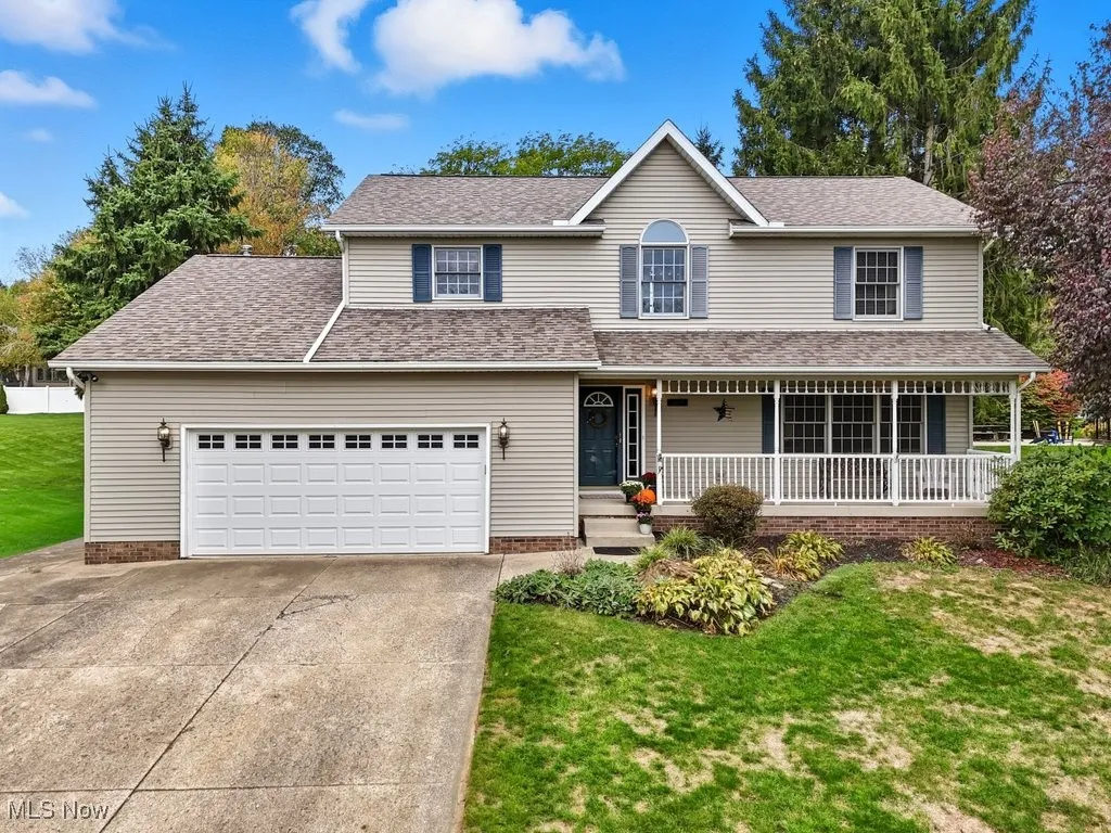 Traditional home with covered porch, a front yard, concrete driveway, a garage, and a shingled roof