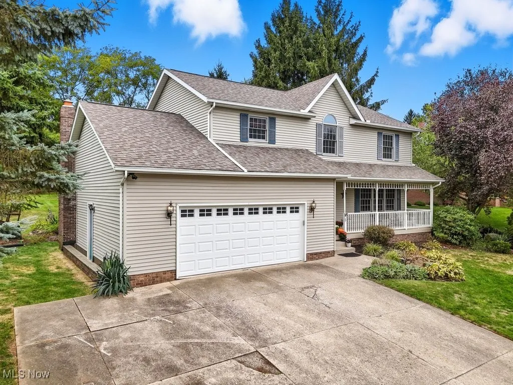 Traditional-style house with a porch, a shingled roof, driveway, and a front lawn