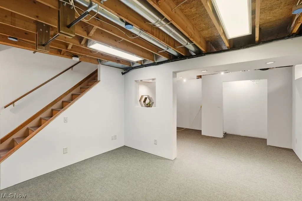 Finished basement featuring stairway and light colored carpet