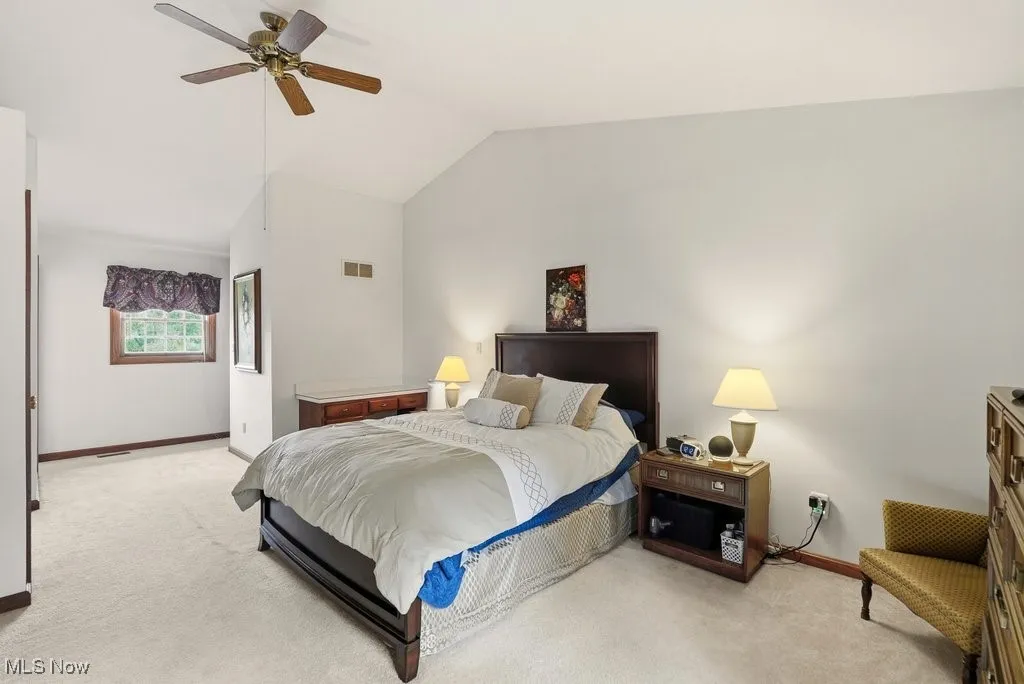 Bedroom featuring vaulted ceiling, light colored carpet, and ceiling fan