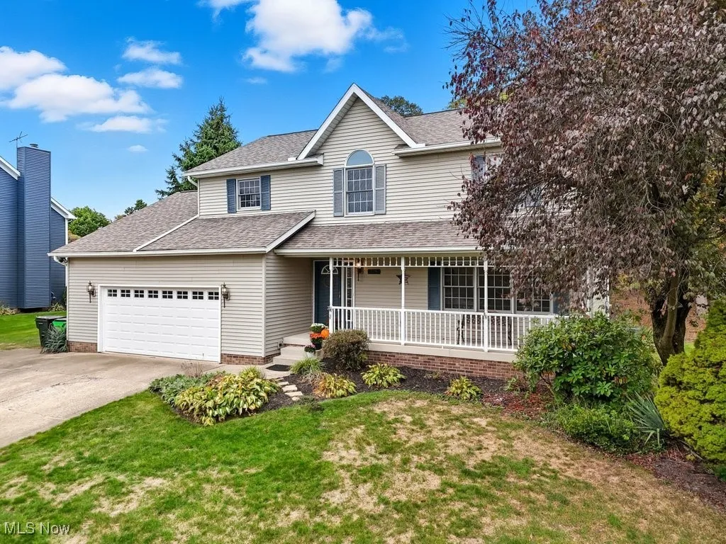 View of front of property with a porch, a front yard, concrete driveway, and a shingled roof