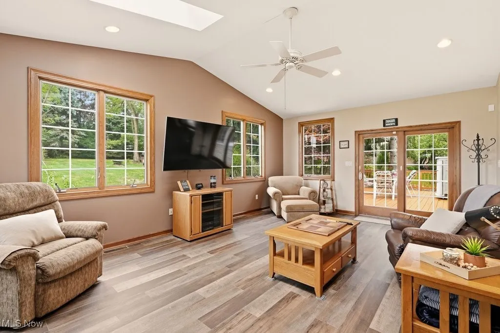 Living area featuring a skylight, healthy amount of natural light, recessed lighting, light wood-style floors, and vaulted ceiling