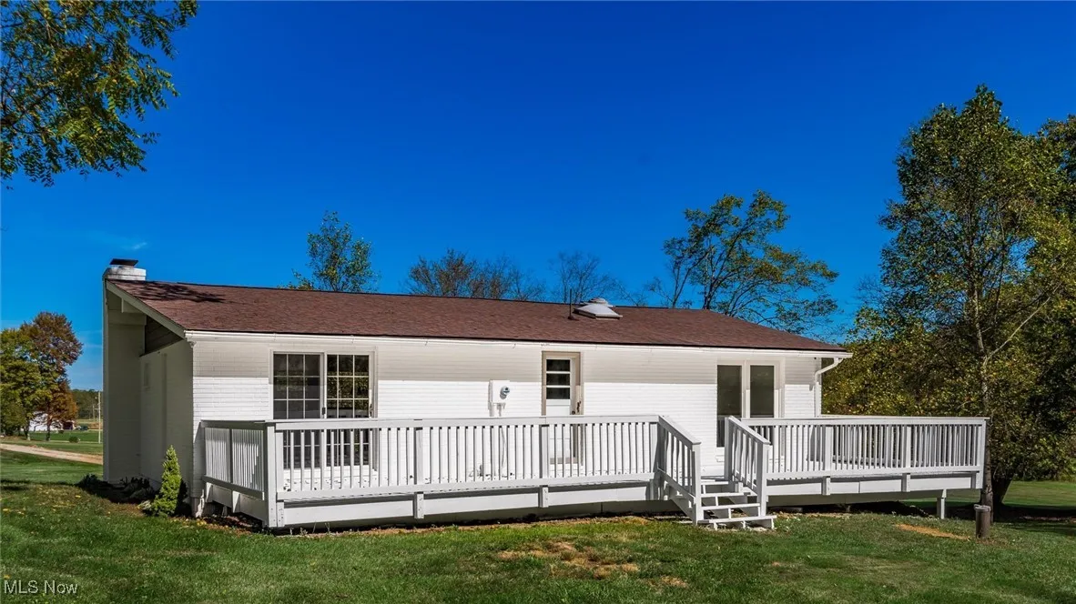 Rear view of house featuring a deck, a yard, and a chimney