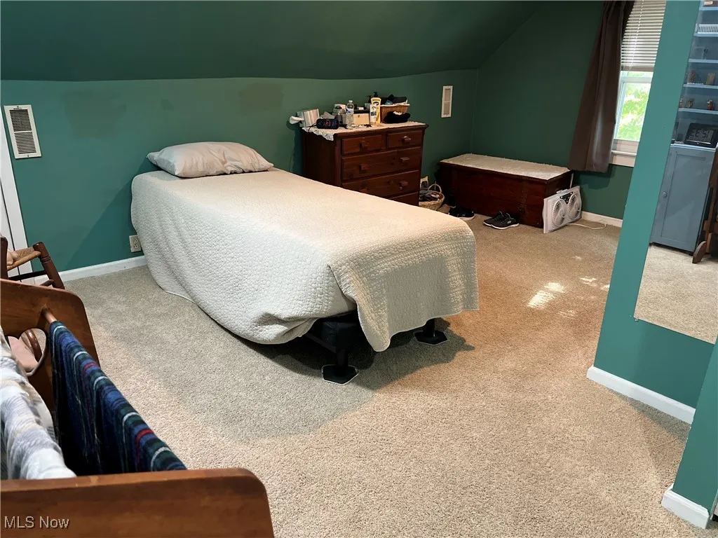 Carpeted bedroom featuring baseboards and vaulted ceiling