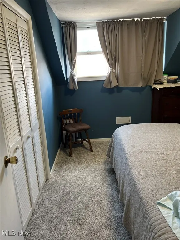 Bedroom with light colored carpet and a closet