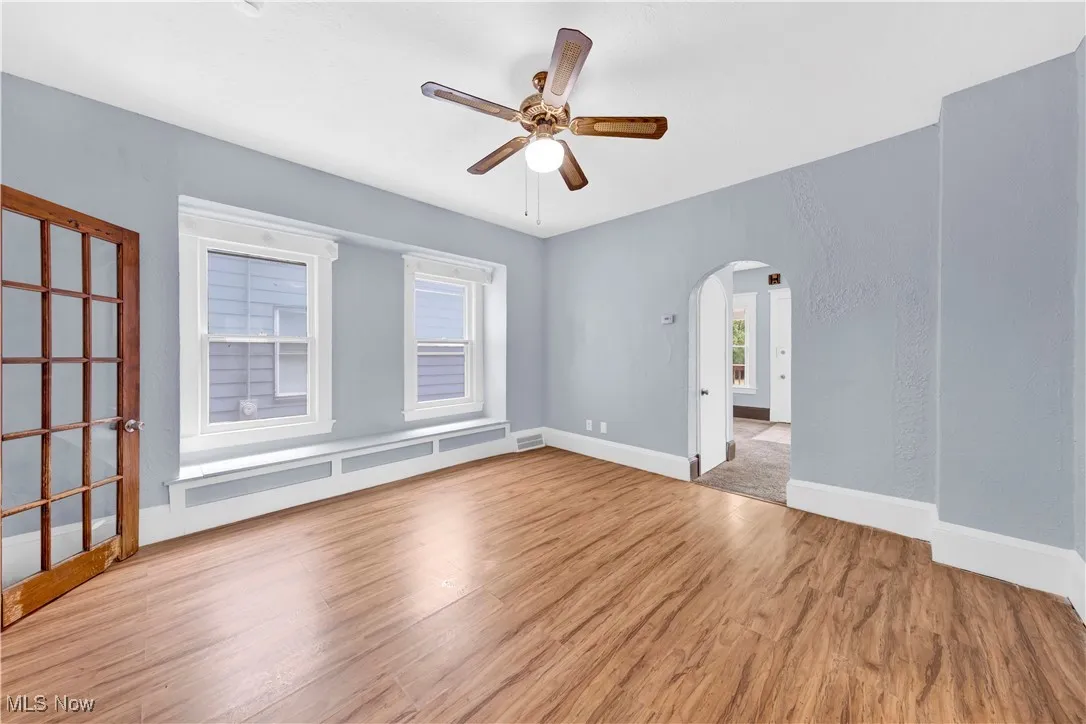 Spare room featuring light wood-type flooring, arched walkways, and ceiling fan