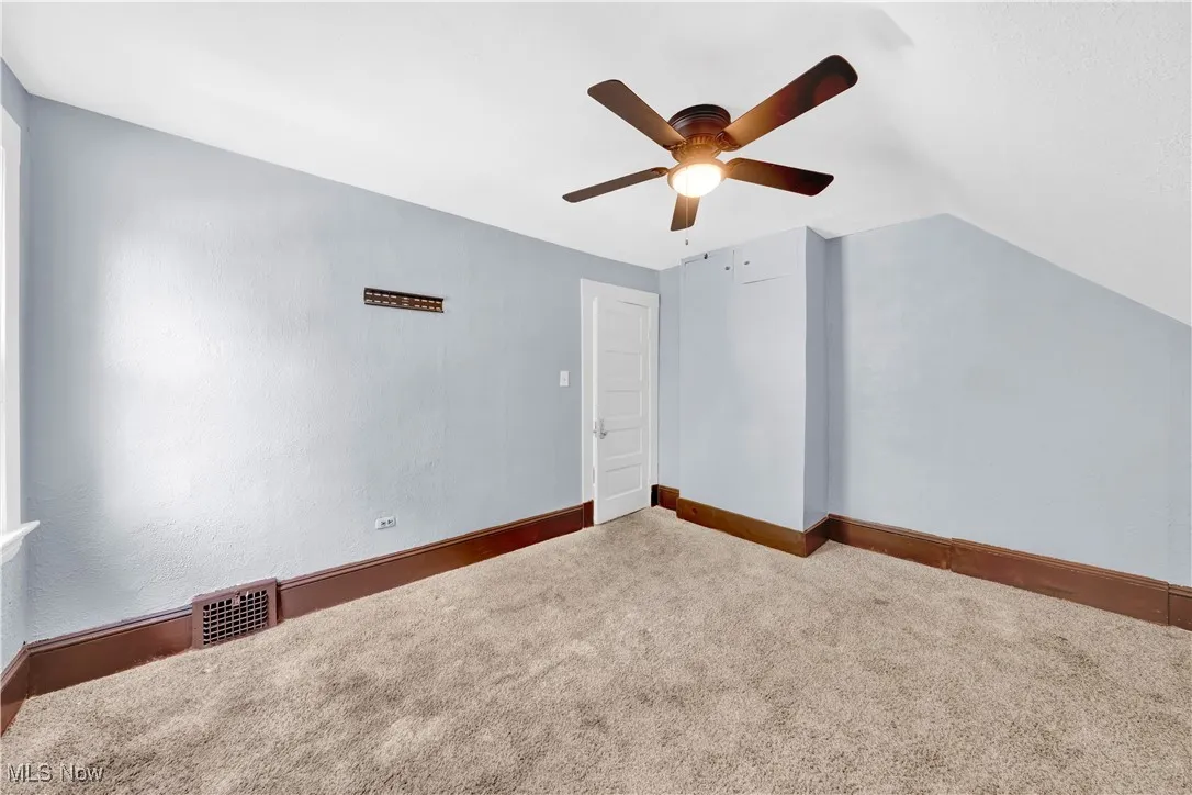 Additional living space featuring carpet, lofted ceiling, and ceiling fan