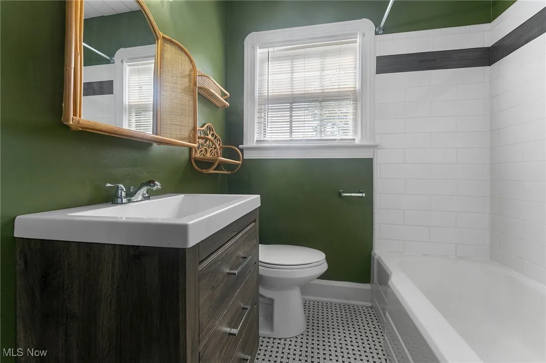 Full bathroom with healthy amount of natural light, shower / bathtub combination, vanity, and light tile patterned floors
