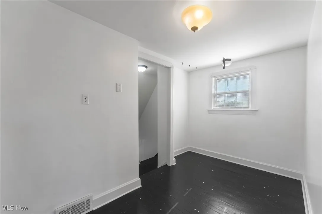 Empty room featuring dark wood-style floors and baseboards