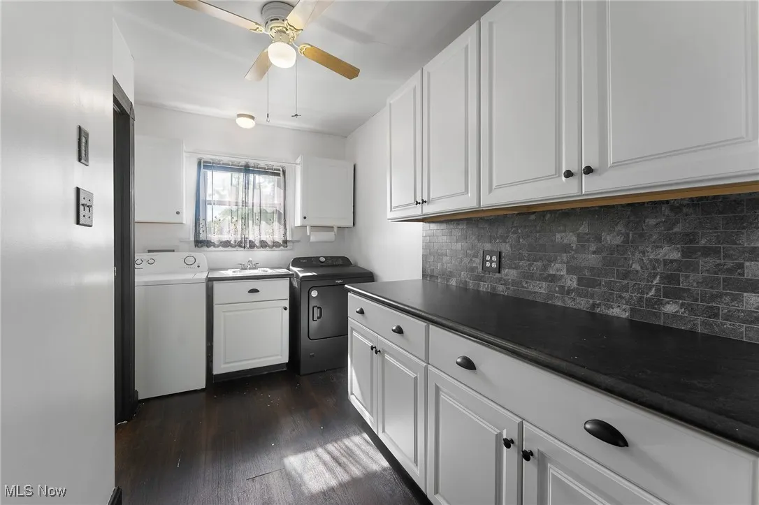 Kitchen with white cabinets, dark countertops, dark wood finished floors, backsplash, and separate washer and dryer
