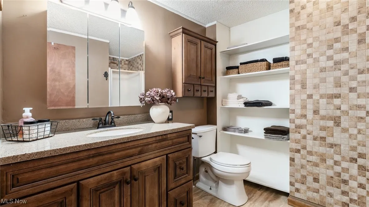 Full bath featuring a textured ceiling, vanity, and a shower