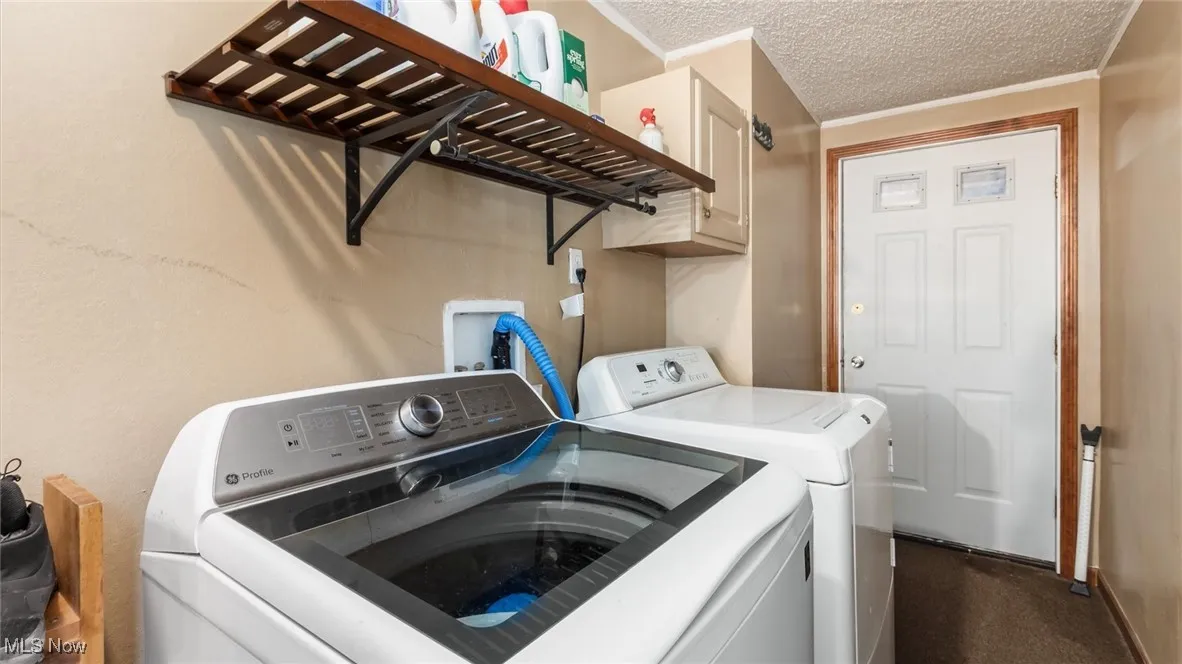 Laundry area with washing machine and dryer, a textured ceiling, and cabinet space